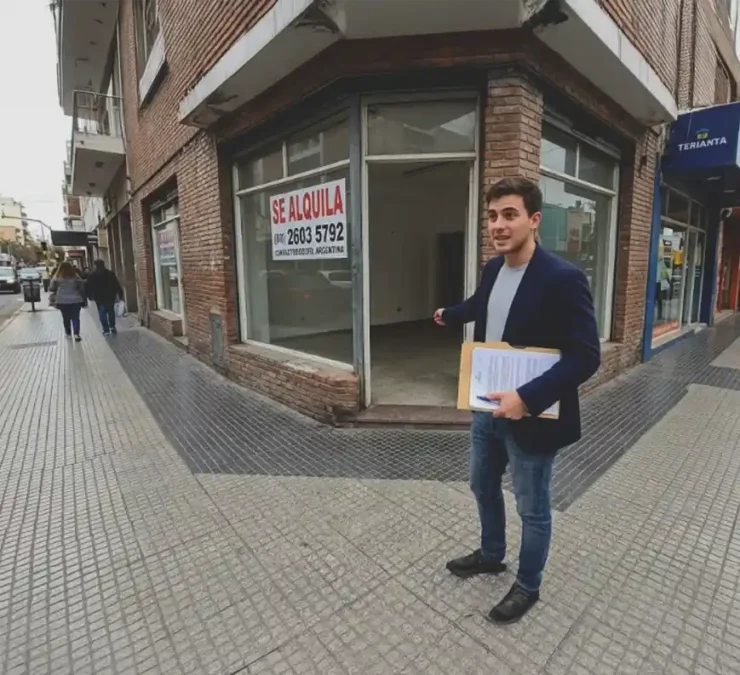 oven emprendedor con carpeta en mano frente a un local comercial en alquiler en el centro de Río Cuarto, a punto de iniciar su trámite de habilitación.